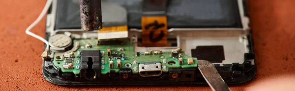 Vista recortada del técnico desmontaje de teléfonos inteligentes durante la reparación en el taller, pancarta horizontal - foto de stock