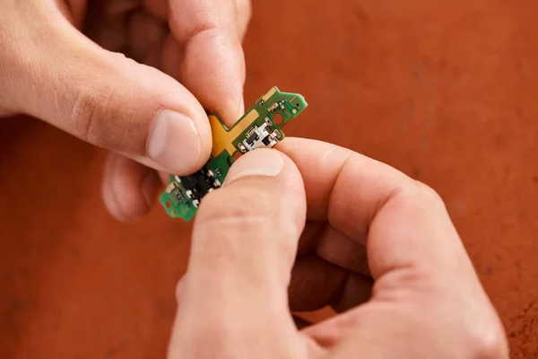 Vue rapprochée des mains d'un technicien professionnel tenant un chipset électronique en atelier de réparation — Photo de stock