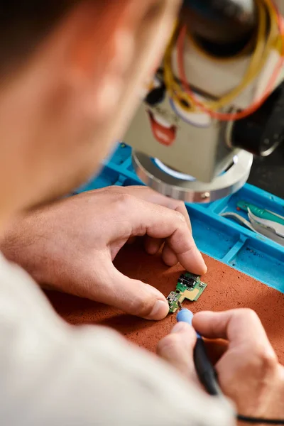 Cropped view of professional technician soldering chipset in repair shop, maintenance service — Stock Photo