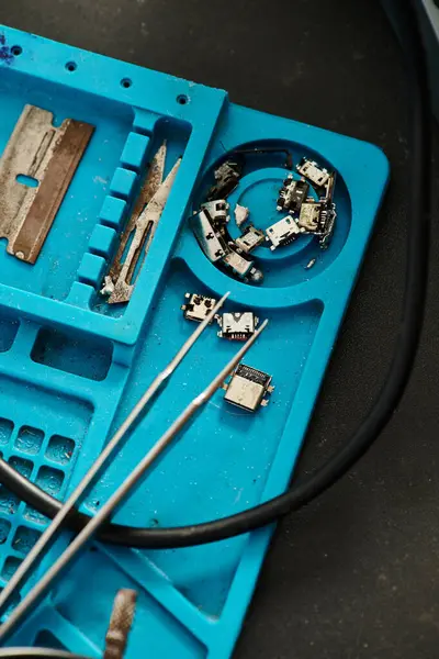 Vista superior de la caja de plástico con diferentes piezas de repuesto para dispositivos electrónicos en taller de reparación - foto de stock