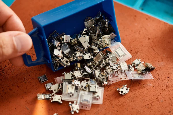 Ausgeschnittene Ansicht eines professionellen Technikers mit Kunststoffbox mit verschiedenen Ersatzteilen in der Werkstatt — Stockfoto