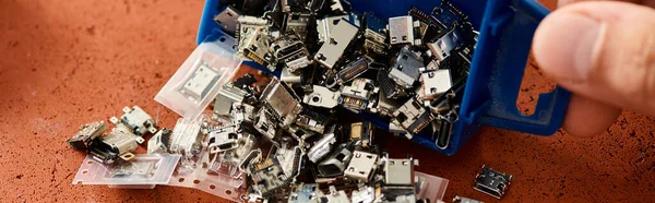 Cropped view of skilled technician with plastic container of various spare parts in workshop, banner — Stock Photo