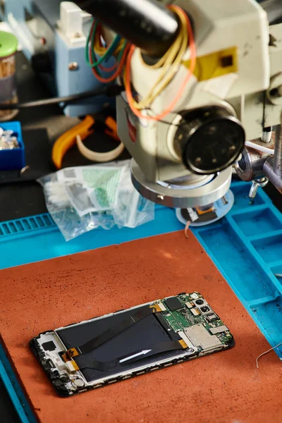 Microscope over mobile phone on table in repair workshop, professional maintenance service business — Stock Photo