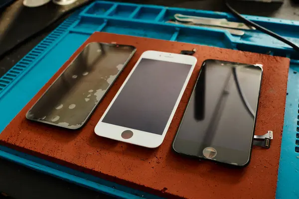 Blick auf kaputte und reparierte Mobiltelefone auf dem Schreibtisch in der Reparaturwerkstatt — Stockfoto