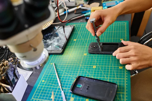 Vue partielle du technicien professionnel avec tournevis réparer téléphone portable dans un atelier privé — Photo de stock
