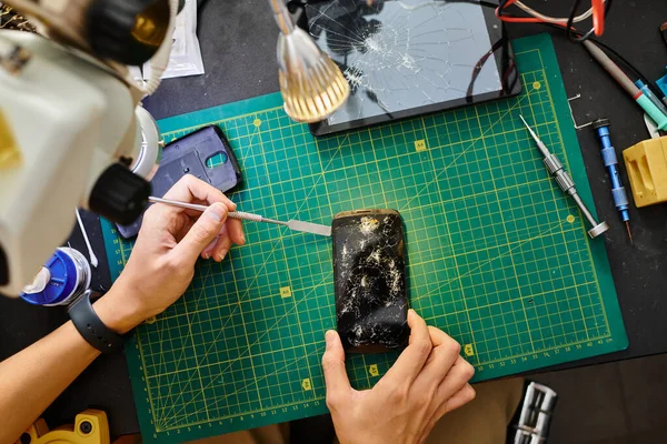 Ausgeschnittene Ansicht eines Reparateurs beim Entfernen des kaputten Touchscreens des Smartphones in der Wartungswerkstatt — Stockfoto