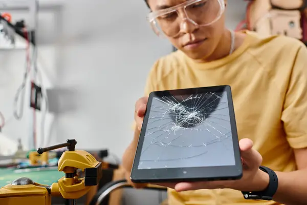 Blurred asian technician in goggles making technical expertise on digital tablet with blank screen — Stock Photo