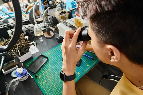 High angle view of skilled repairman working with microscope and electronic equipment in workshop — Stock Photo