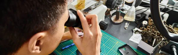 Specialista tecnico con microscopio vicino all'attrezzatura elettronica in officina, vista ad alto angolo, banner — Foto stock