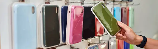 Cropped view of seller near showcase with choice of colorful phone cases, small business, banner — Stock Photo