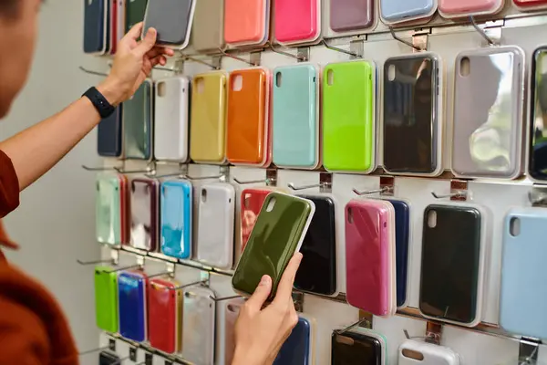 Vista recortada del vendedor elegir caja de teléfono colorido de surtido en tienda privada - foto de stock