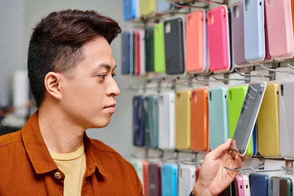 Empresario asiático mirando colorido teléfono caso de escaparate de tienda privada, pequeña empresa - foto de stock