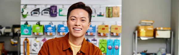 Feliz éxito asiático empresario mirando cámara en privado electrónica tienda, horizontal banner - foto de stock