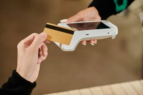 Cliente segurando cartão de crédito perto leitor de cartão sem contato, mão cortada de homem pagando no café vegan — Fotografia de Stock