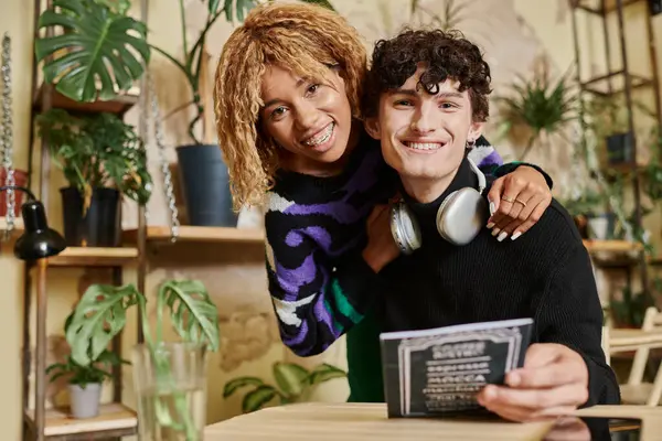 Young affectionate african american woman embracing her curly boyfriend near menu in vegan cafe — Stock Photo