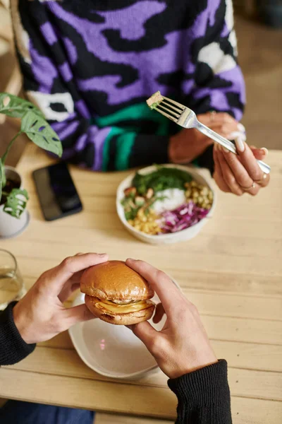 Colpo ritagliato di giovane e diversificata coppia godendo pasto vegan in caffè, hamburger con tofu e insalata — Foto stock