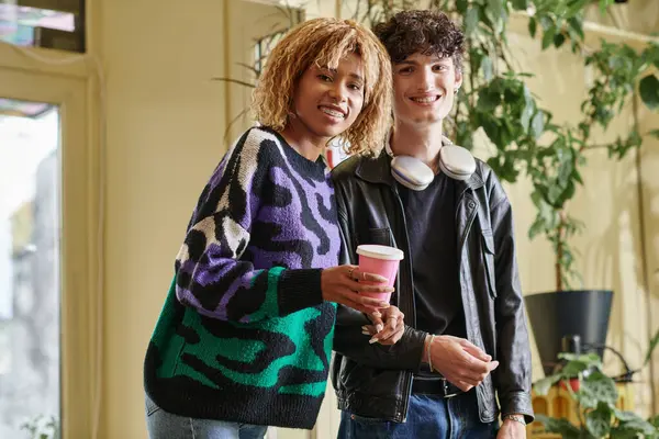 Couple joyeux et diversifié en tenue décontractée regardant la caméra tout en se tenant ensemble dans un café végétalien — Photo de stock