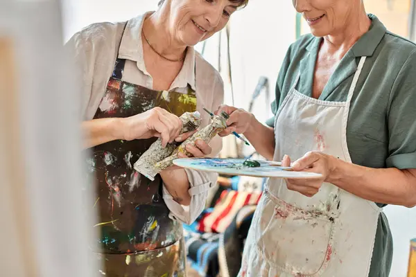 Smiling mature women mixing paints on color palette during painting master class in art studio — Stock Photo
