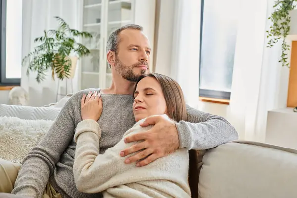 Pleased child-free couple embracing on cozy couch in modern living room, calm lifestyle and serenity — Stock Photo