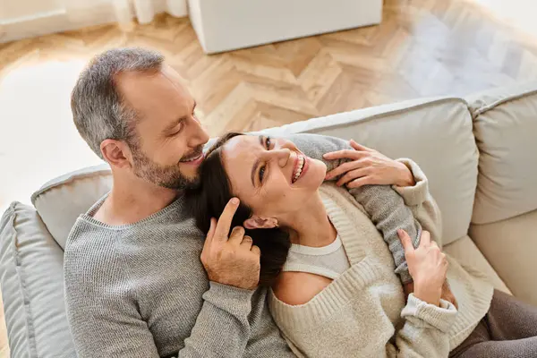 Aus der Vogelperspektive: fröhliche Frau lacht neben Ehemann auf Sofa im Wohnzimmer, kinderfreies Paar — Stockfoto