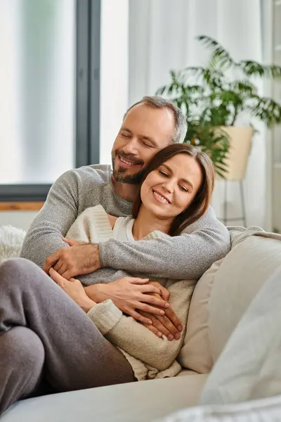 Glückliches kinderfreies Paar umarmt und lächelt mit geschlossenen Augen auf Couch im Wohnzimmer, Liebe und Freude — Stockfoto