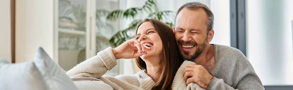 Marido rindo com os olhos fechados abraçando na acolhedora sala de estar em casa, casal sem filhos, banner — Fotografia de Stock
