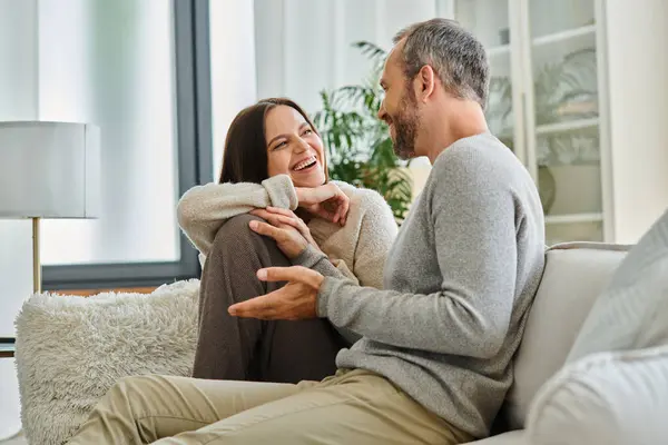 Joyful child-free couple talking on couch in modern living room, quality time at cozy home — Stock Photo