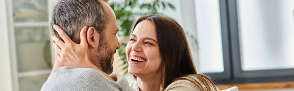 Mujer riendo abrazando marido en acogedora sala de estar en casa, pareja libre de niños, pancarta horizontal - foto de stock