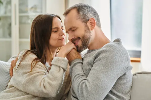 Happy man with closed eyes kissing hands of delighted wife in living room, love and tenderness — Stock Photo