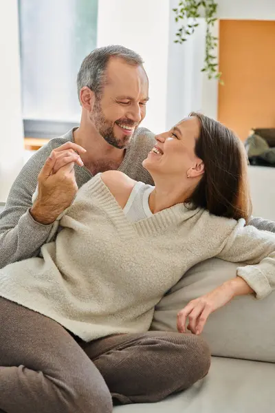 Smiling child-free couple holding hands and smiling on cozy couch in living room unity and harmony — Stock Photo