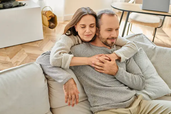 Femme heureuse avec les yeux fermés embrassant l'homme assis sur le canapé dans le salon, couple sans enfant — Photo de stock