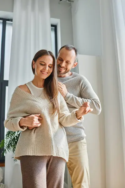 Hombre sonriente abrazando esposa feliz en la sala de estar moderna en el hogar acogedor, estilo de vida moderno libre de niños - foto de stock