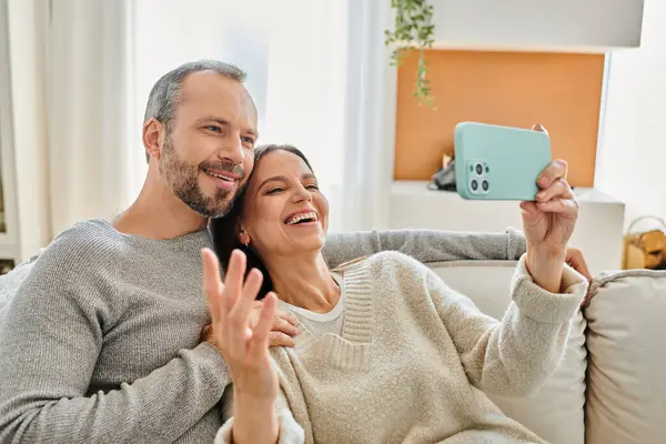Cheerful woman taking selfie on smartphone with husband in living room, leisure of child-free couple — Stock Photo