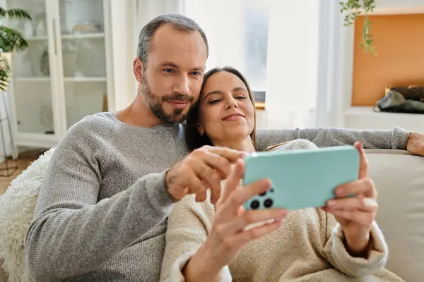Carefree child-free couple relaxing and browsing internet on mobile phone at home, quality time — Stock Photo