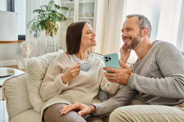 Liebevolle Ehefrau mit Kaffeetasse rührendes Gesicht des glücklichen Mannes auf der Couch im Wohnzimmer, kinderfreies Leben — Stockfoto