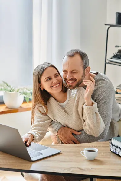 Hombre emocionado abrazando esposa feliz que trabaja en el ordenador portátil en casa, el cuidado y el apoyo de la pareja libre de niños - foto de stock