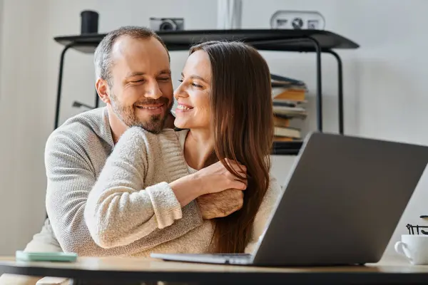 Marido feliz abraçando esposa alegre trabalhando no laptop em casa, cuidado e apoio do casal livre de crianças — Fotografia de Stock