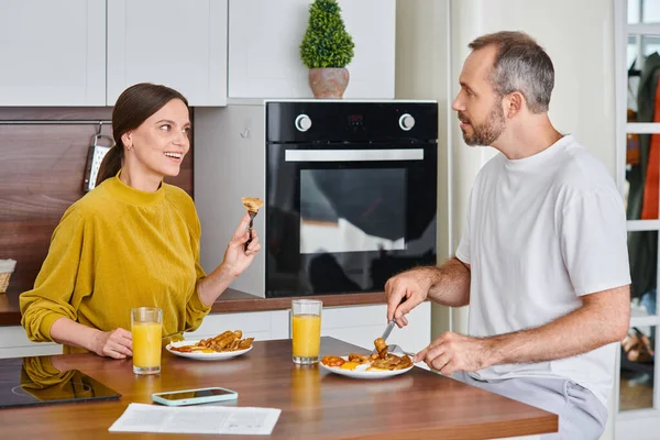 Smiling child-free couple talking during delicious breakfast in modern kitchen, serenity and unity — Stock Photo