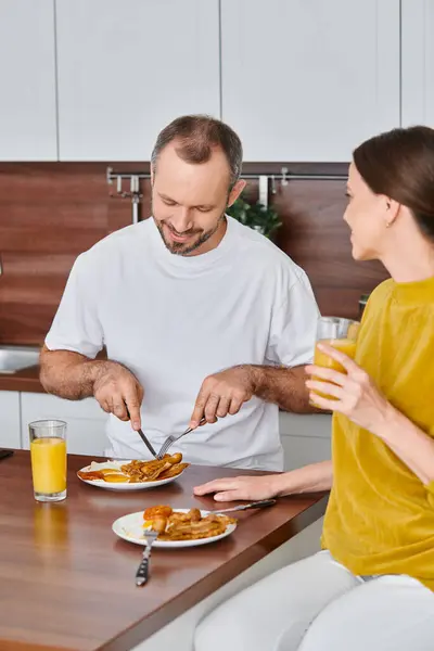Happy man having delicious breakfast near wife in modern kitchen, morning of child-free couple — Stock Photo