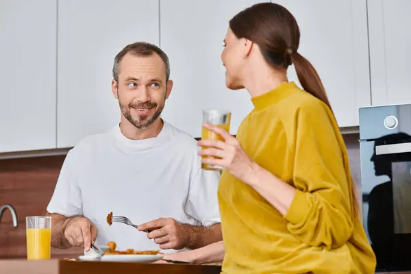 Homme souriant ayant délicieux petit déjeuner près de la femme avec du jus d'orange dans la cuisine, mode de vie sans enfant — Photo de stock