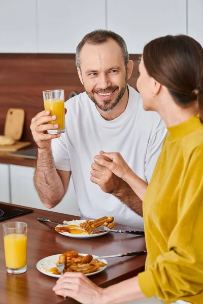 Pareja sin niños encantados tomados de la mano durante el desayuno en la acogedora cocina en casa, la felicidad - foto de stock