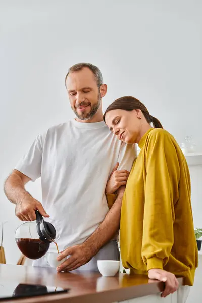 Fürsorglicher Mann gießt frischen aromatischen Kaffee in der Nähe der glücklichen Frau in die Küche, Morgen des kinderfreien Paares — Stockfoto
