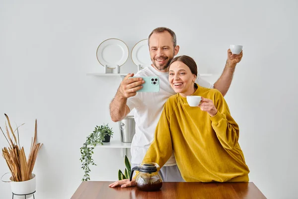 Aufgeregtes kinderfreies Paar spricht beim Morgenkaffee in der Küche Selbstporträt auf Smartphone — Stockfoto