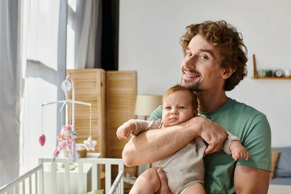 Кучеряве волосся і щасливий батько тримає в руках свого маленького сина в затишній спальні вдома, батьківство — стокове фото
