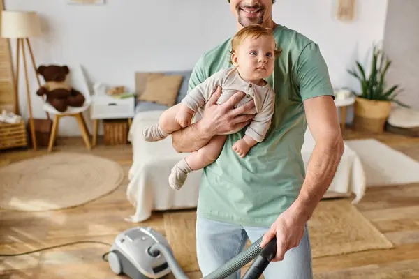 Beschnitten Mann Multitasking-Hausarbeit und Kinderbetreuung, glücklicher Vater staubsaugt Haus mit Sohn in den Armen — Stockfoto
