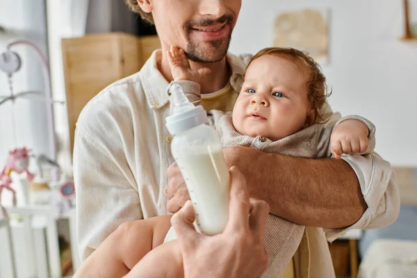 Pai feliz alimentando atentamente seu filho bebê com leite em mamadeira, paternidade e cuidado — Fotografia de Stock