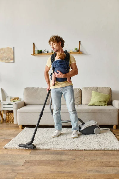 Père avec bébé garçon dans porteur aspirateur appartement à la maison, propreté et travaux ménagers — Photo de stock