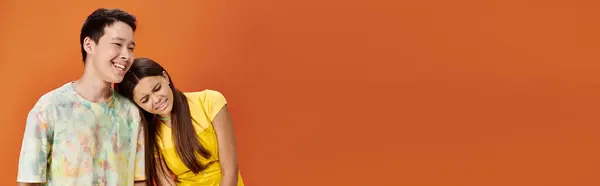 Jolly diverse teens in bold attires posing together with head on shoulder on orange backdrop, banner — Stock Photo