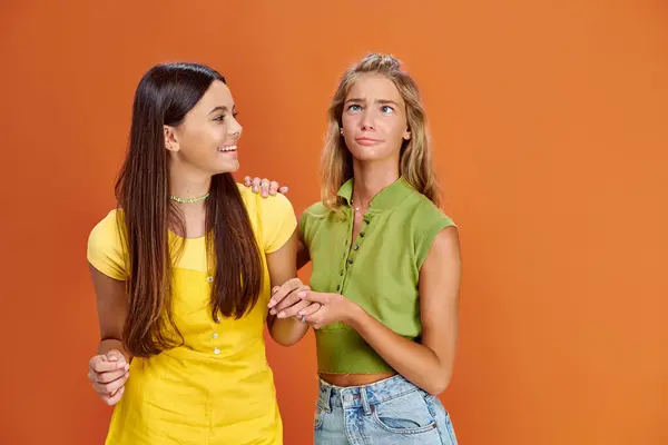 Adorable jolly teens in casual vibrant attires having fun on orange backdrop, friendship day — Stock Photo