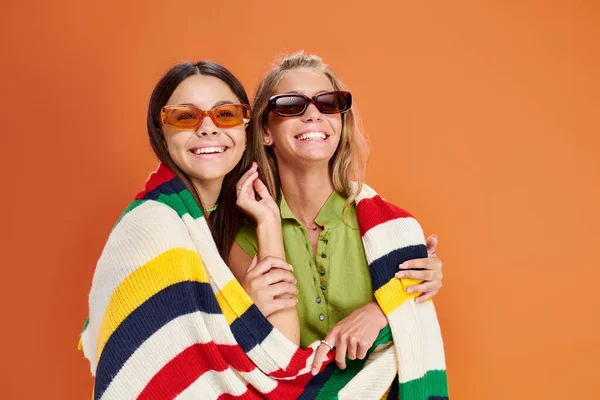 Cheerful blonde and brunette teenage girls with sunglasses hugging and looking at camera, friendship — Stock Photo
